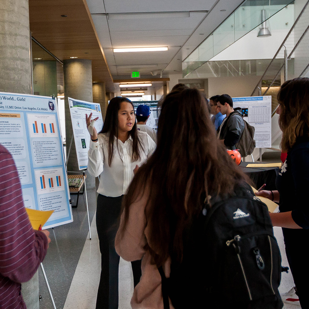 student presents posterboard project to another student
